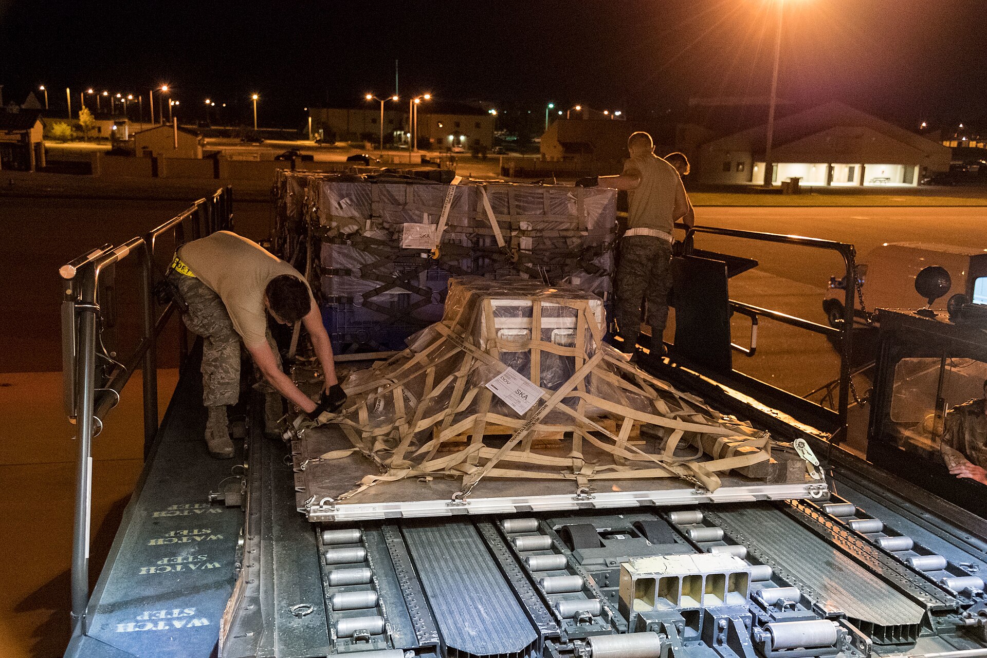 A cargo pallet being loaded into an aircraft at night